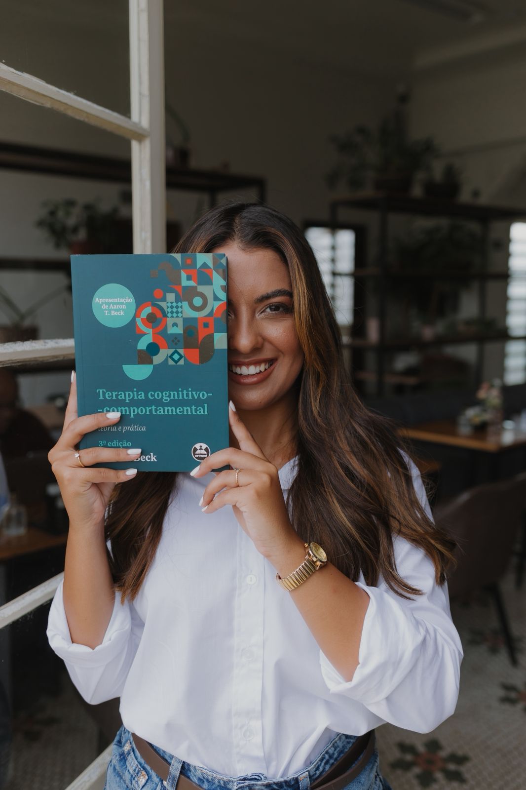 Amanda Prado segurando o livro de Terapia Cognitivo-Comportamental de Judith Beck