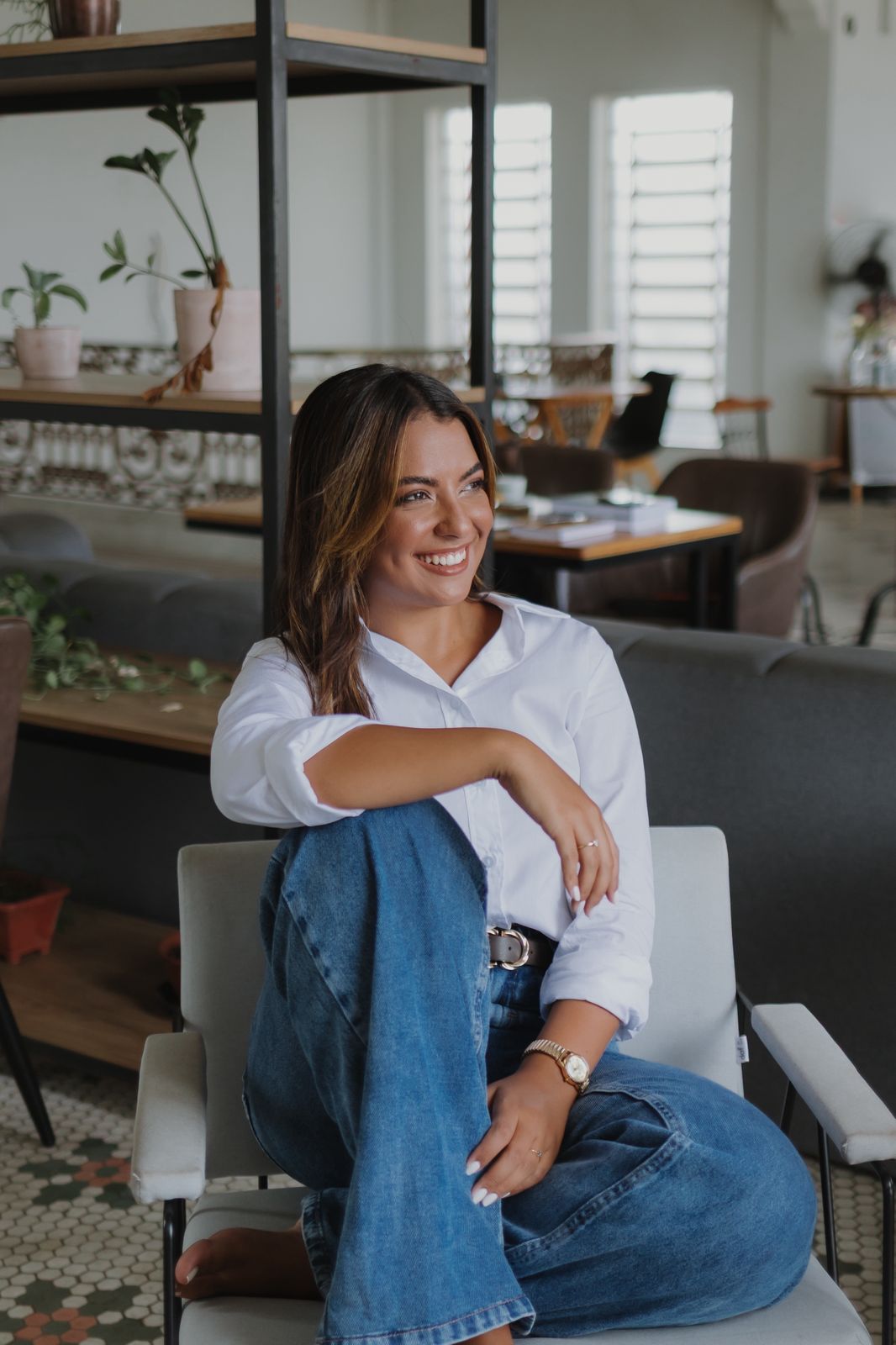 Amanda Prado sentada em uma poltrona, sorrindo de forma acolhedora